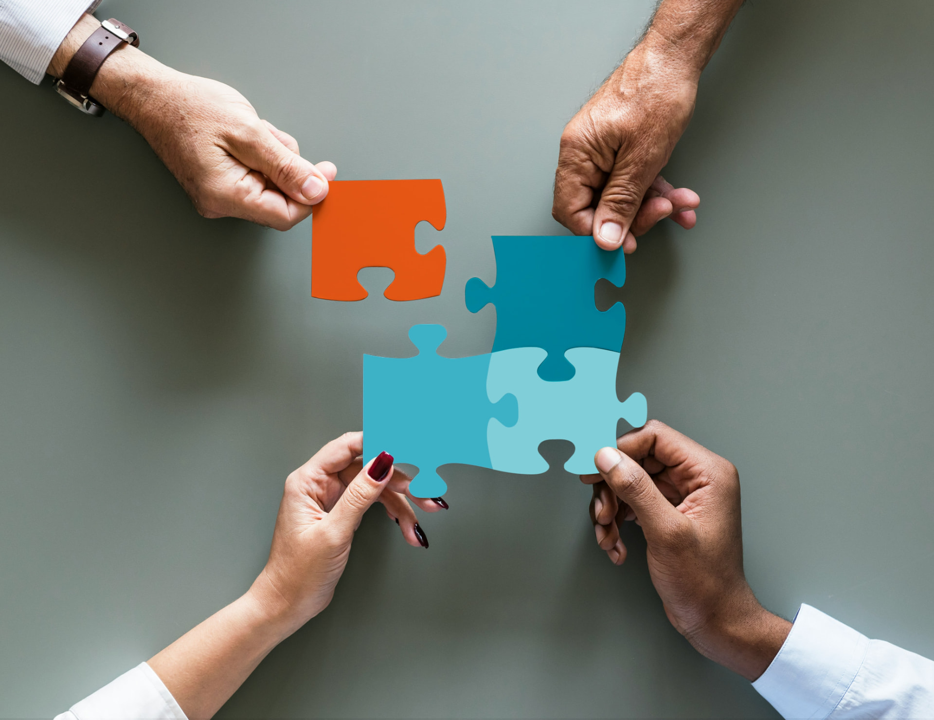 Four people joining the last piece of a puzzle together